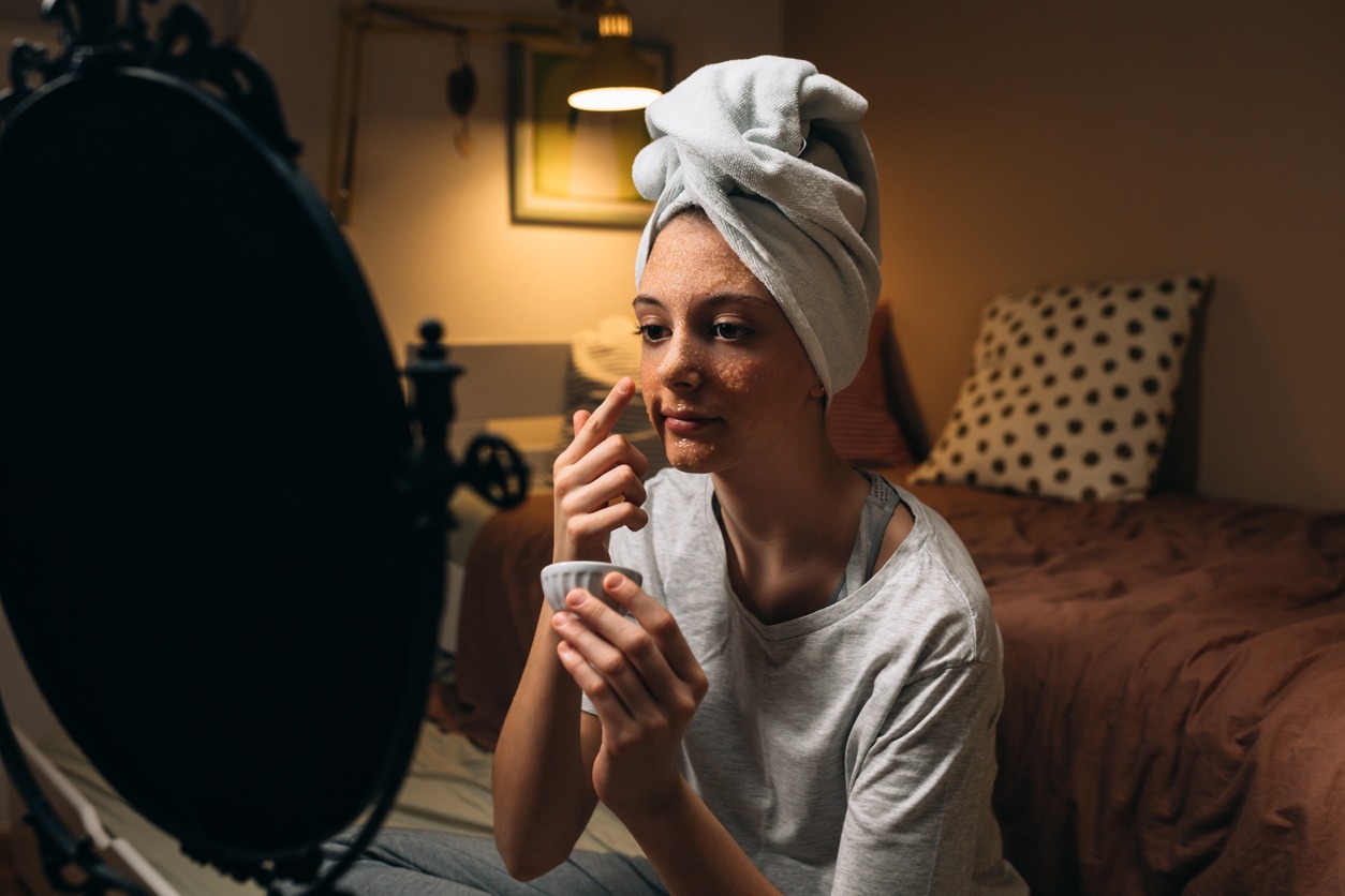 Girl at home applying a cosmetic face mask