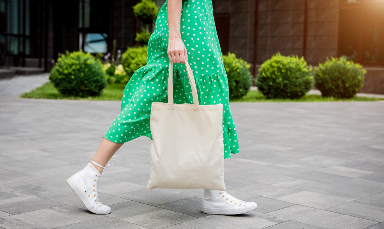 Young beautiful woman with linen eco bag on city background